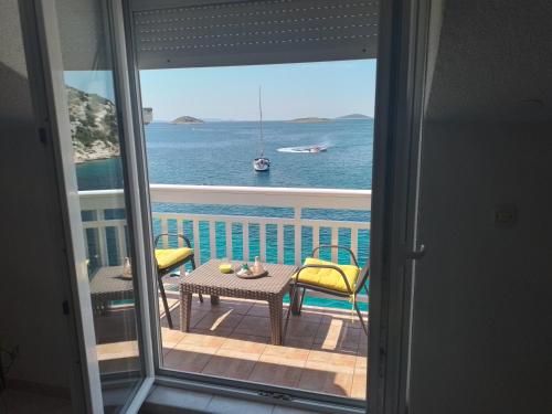 a view of the ocean from a balcony with a table and chairs at Apartments Uvala Murtar in Jezera