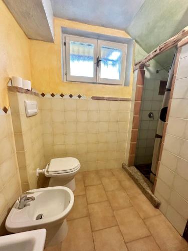 a bathroom with a toilet and a sink and a window at Tentadore in La Caletta