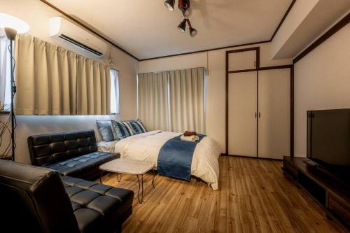 a bedroom with a bed and a couch and a tv at 渋谷まで電車で1駅 2分池尻大橋駅まで徒歩8分民泊アパート in Tokyo
