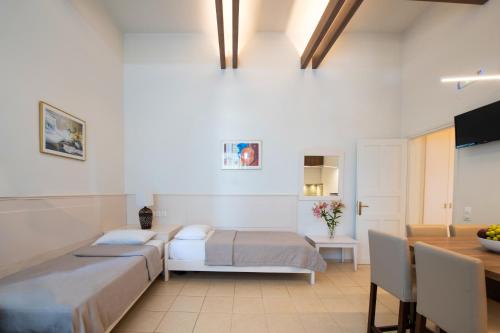 a bedroom with two beds and a table and a dining room at Captain's House Hotel Suites & Apartments in Panormos Rethymno