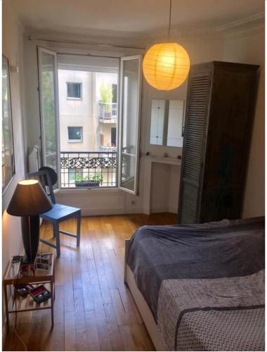 une chambre avec un lit, une lampe et une fenêtre dans l'établissement Charmant appartement à Montmartre, à Paris