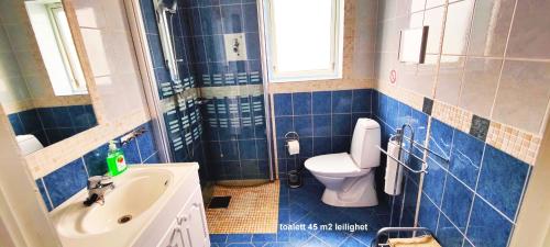 Baño de azulejos azules con aseo y lavamanos en Helt i Vannkanten as, en Åkrehamn