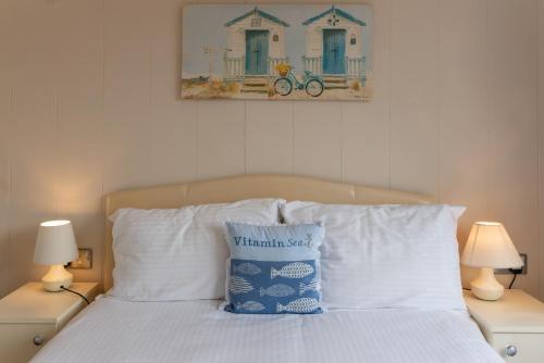 1 cama con almohadas blancas y una foto en la pared en Driftwood Lodge, en Ilfracombe