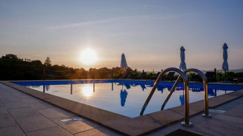 a swimming pool with the sun setting in the background at Quinta de Real in Valença