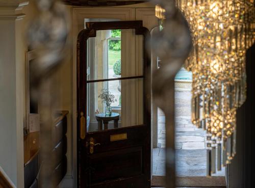 a hallway with a door with a mirror and chandelier at Montigo Resorts, Somerset in Shepton Mallet