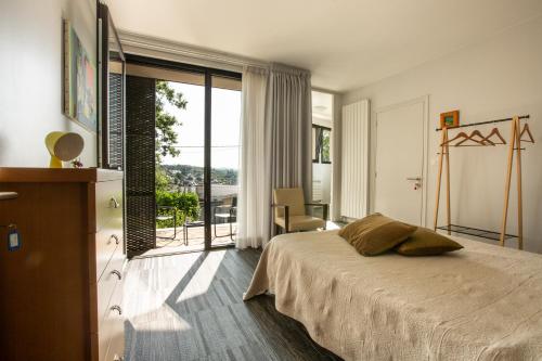 a bedroom with a bed and a view of a balcony at Chambre BEAUSEJOUR in Brive-la-Gaillarde