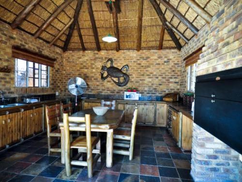 a kitchen with a table and chairs and a brick wall at Mokuru Private Nature Reserve in Brits