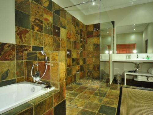 La grande salle de bains est pourvue d'une baignoire et d'une douche. dans l'établissement Mokuru Private Nature Reserve, à Brits