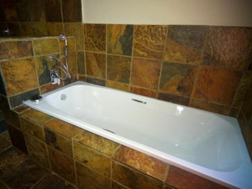 a white bath tub in a tiled bathroom at Mokuru Private Nature Reserve in Brits