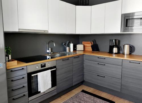 a kitchen with white cabinets and stainless steel appliances at Trendy apartment in the heart of green Lahti, free parking in Lahti
