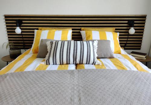 a bed with yellow and white striped sheets and pillows at Trendy apartment in the heart of green Lahti, free parking in Lahti