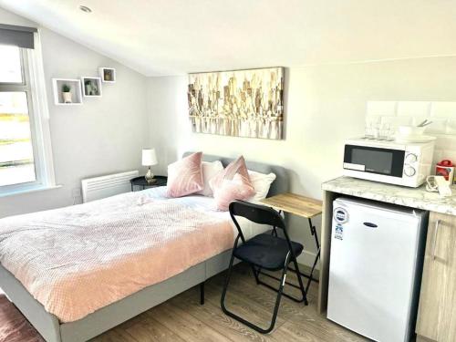 a bedroom with a bed and a desk with a microwave at Southall Stays near Heathrow UB2 in Southall