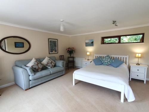 a bedroom with a bed and a couch and a mirror at Meadow View in Sidmouth
