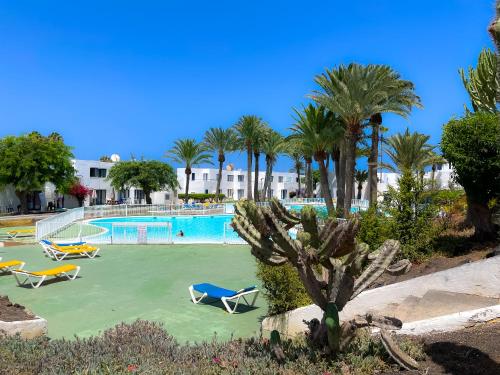una piscina con sedie e palme di Los Barqueros 24 by Best Holidays Fuerteventura a Corralejo