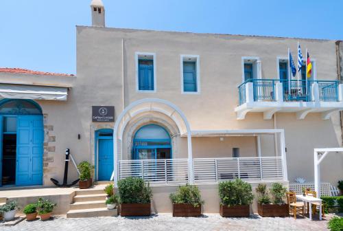 a building with blue doors and a balcony at Captain's House Hotel Suites & Apartments in Panormos Rethymno