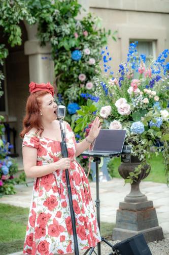 a woman in a dress singing into a microphone at Montigo Resorts, Somerset in Shepton Mallet