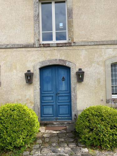 a blue door on a building with two bushes at La Ptite Normande in Saint-Germain-de-Tournebut