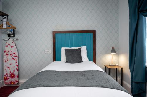 a bedroom with a large bed with a blue headboard at Rising Sun Hotel by Greene King Inns in Cheltenham