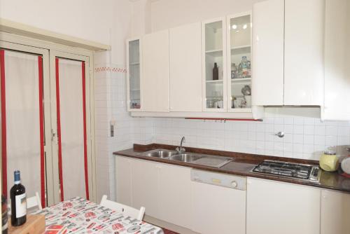 a kitchen with white cabinets and a sink and a table at Room in Guest room - Emilios home Triple room in our cozy and comfortable establishment in Rome