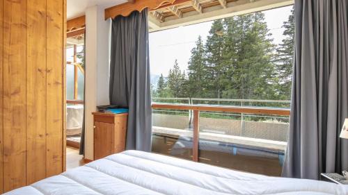 a bedroom with a bed and a large window at V DU BACHAT - Silene D11 in Chamrousse