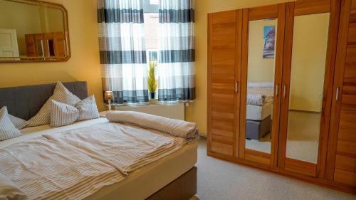 Schlafzimmer mit einem Bett, einem Spiegel und einem Fenster in der Unterkunft Ferienwohnung Bubikat in Borkum