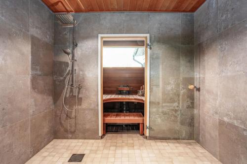 un baño con ducha y una puerta de cristal que bloquea la entrada. en Villa Syreeni - Seafront/Jacuzzi, 