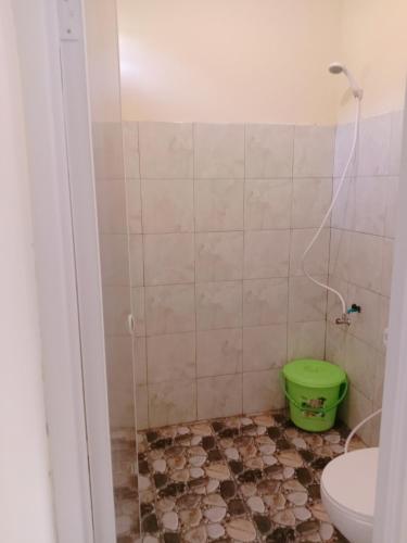 a bathroom with a toilet and a green bucket at Rumah Ukhi Guest House in Yogyakarta