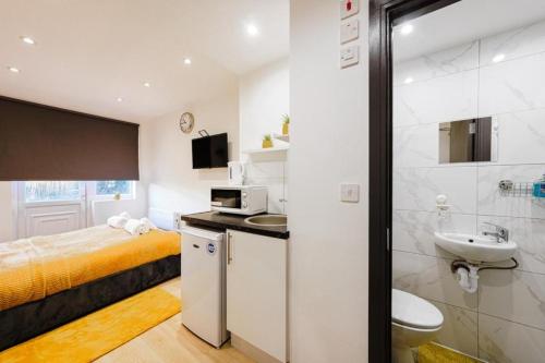 a small bathroom with a bed and a sink at UB2 Suites - Heathrow London in Southall