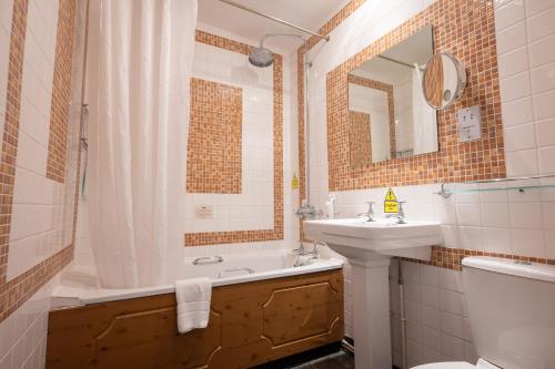 y baño con bañera, lavabo y aseo. en Rising Sun Hotel by Greene King Inns en Cheltenham