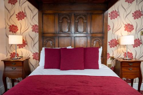 a bedroom with a large bed with red pillows at Rising Sun Hotel by Greene King Inns in Cheltenham