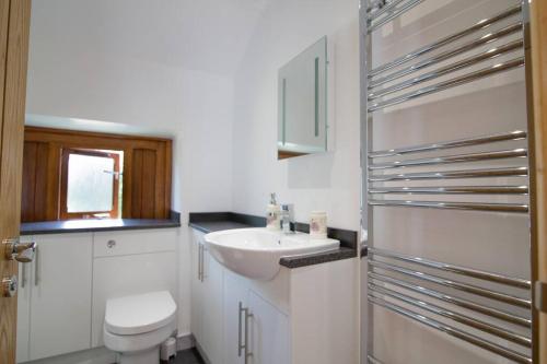 a white bathroom with a sink and a toilet at Piglets. Spacious, Modern, Peaceful, nr Port Isaac in Camelford