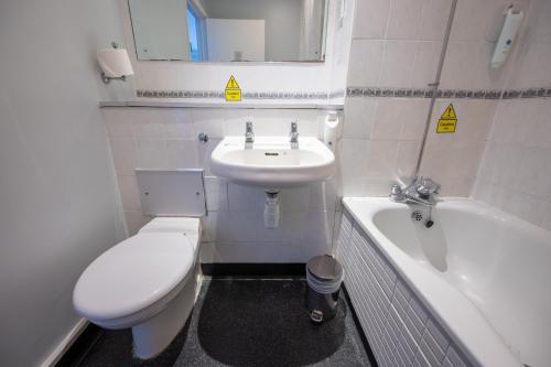 a bathroom with a toilet and a sink and a tub at Rising Sun Hotel by Greene King Inns in Cheltenham