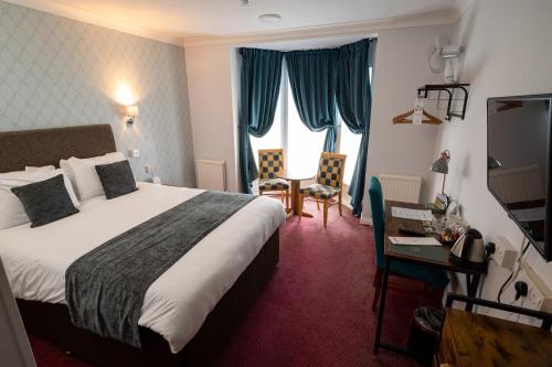チェルトナムにあるRising Sun Hotel by Greene King Innsのベッドとデスクが備わるホテルルームです。