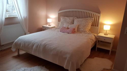 a bedroom with a large white bed with two lamps at Seeblick in Klein Upahl