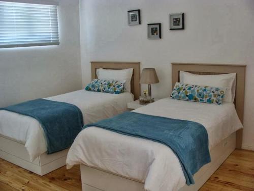 a bedroom with two beds with blue sheets at ZEN Tree bed & breakfast in Paarl