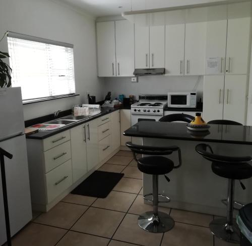 a kitchen with white cabinets and a counter with stools at ZEN Tree bed & breakfast in Paarl