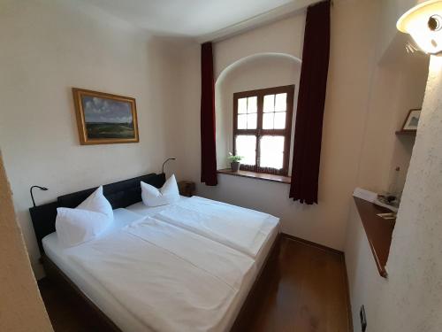 a bedroom with a white bed with a window at Schloss Schänke garni in Bautzen