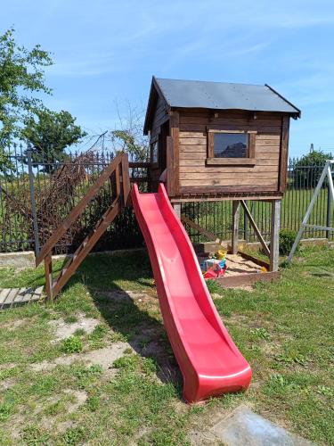 a red slide in front of a play house at Pokoj agroturystyczny in Mieroszyno