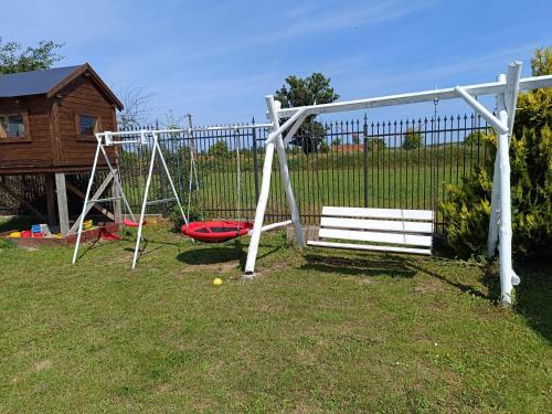 a white swing set in a yard next to a fence at Pokoj agroturystyczny in Mieroszyno