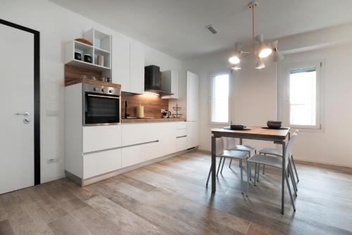 una cocina con armarios blancos y una mesa con sillas. en Residence Cavalli, en Mestre