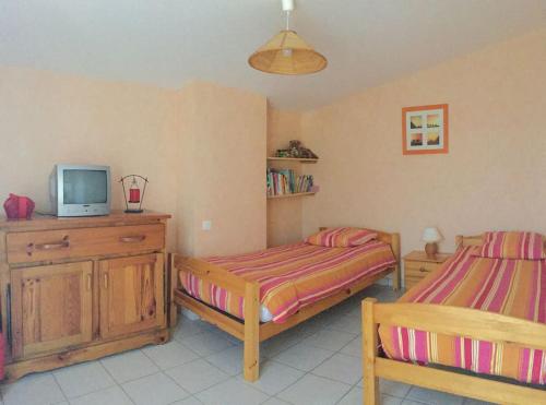 - une chambre avec 2 lits et une télévision sur une armoire dans l'établissement Maison ensoleillée pour 4 à 6 pers, à Saint-Georges-de-Didonne