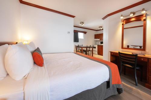 a bedroom with a bed and a desk and a mirror at Hotel Plante in Gaspé