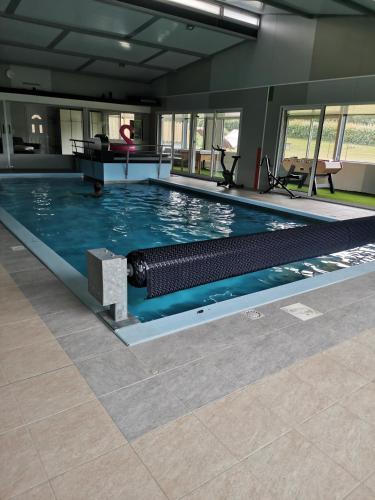 une grande piscine avec de l'eau bleue dans un immeuble dans l'établissement gite piscine campagne, à Saint-Sauveur-des-Landes