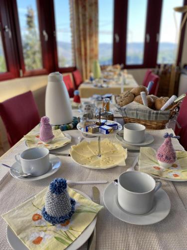 Una mesa larga con platos, tazas y cuencos sobre ella. en Haus Adams - das Wohlfühl Gästehaus, en Boppard