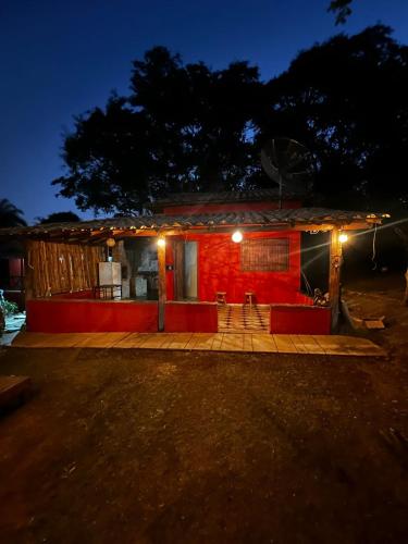 a small house with a red facade at night at Cantinhos do Cipó - Chales privativos com hidro in Serra do Cipo