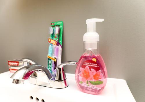 a pink bottle of toothpaste and a toothbrush on a sink at HoMa Homestay Hotel by Olympic Stadium Montreal Auberge-Hostel in Montréal