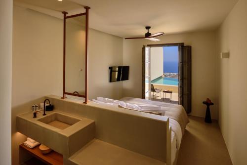 bagno con lavandino, letto e specchio di Elessa Hotel a Pyrgos