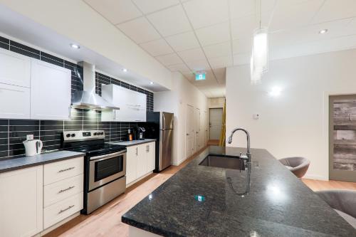 a kitchen with white cabinets and a black counter top at HoMa Homestay Hotel by Olympic Stadium Montreal Auberge-Hostel in Montréal