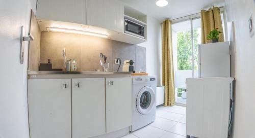 une cuisine avec des armoires blanches et une laveuse et une sécheuse dans l'établissement 2 pièces Confortable proche Paris, à Villemomble