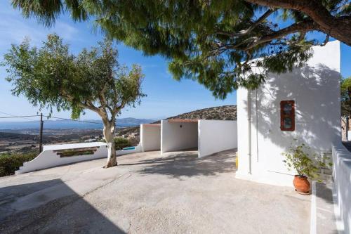 a white building with a tree next to it at The Eagle's Nest house - overlooking Antiparos in Kamári